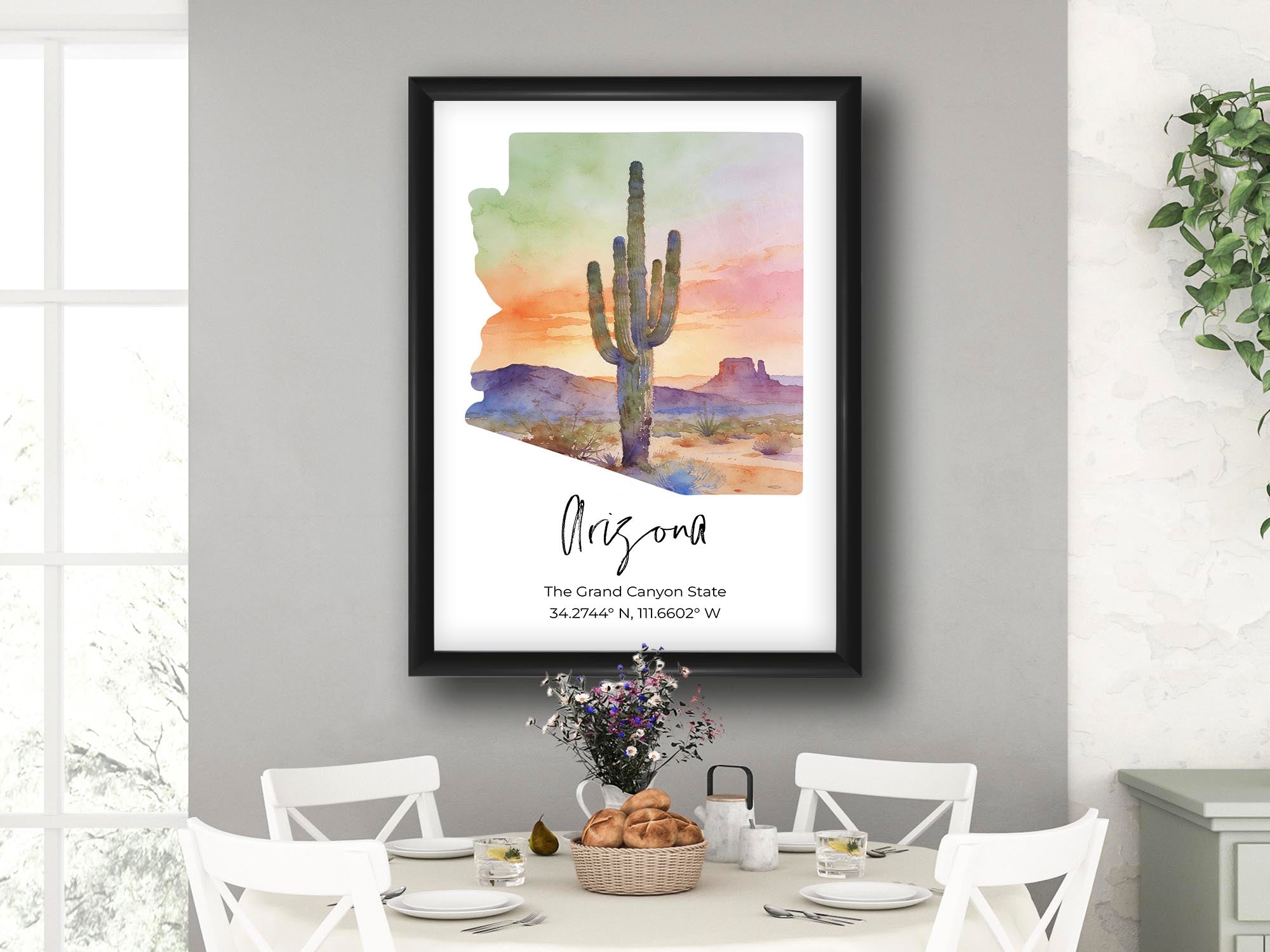 Arizona watercolor state map with cactus sunset wall art print in black frame styled above a table and chairs in a bright dining room