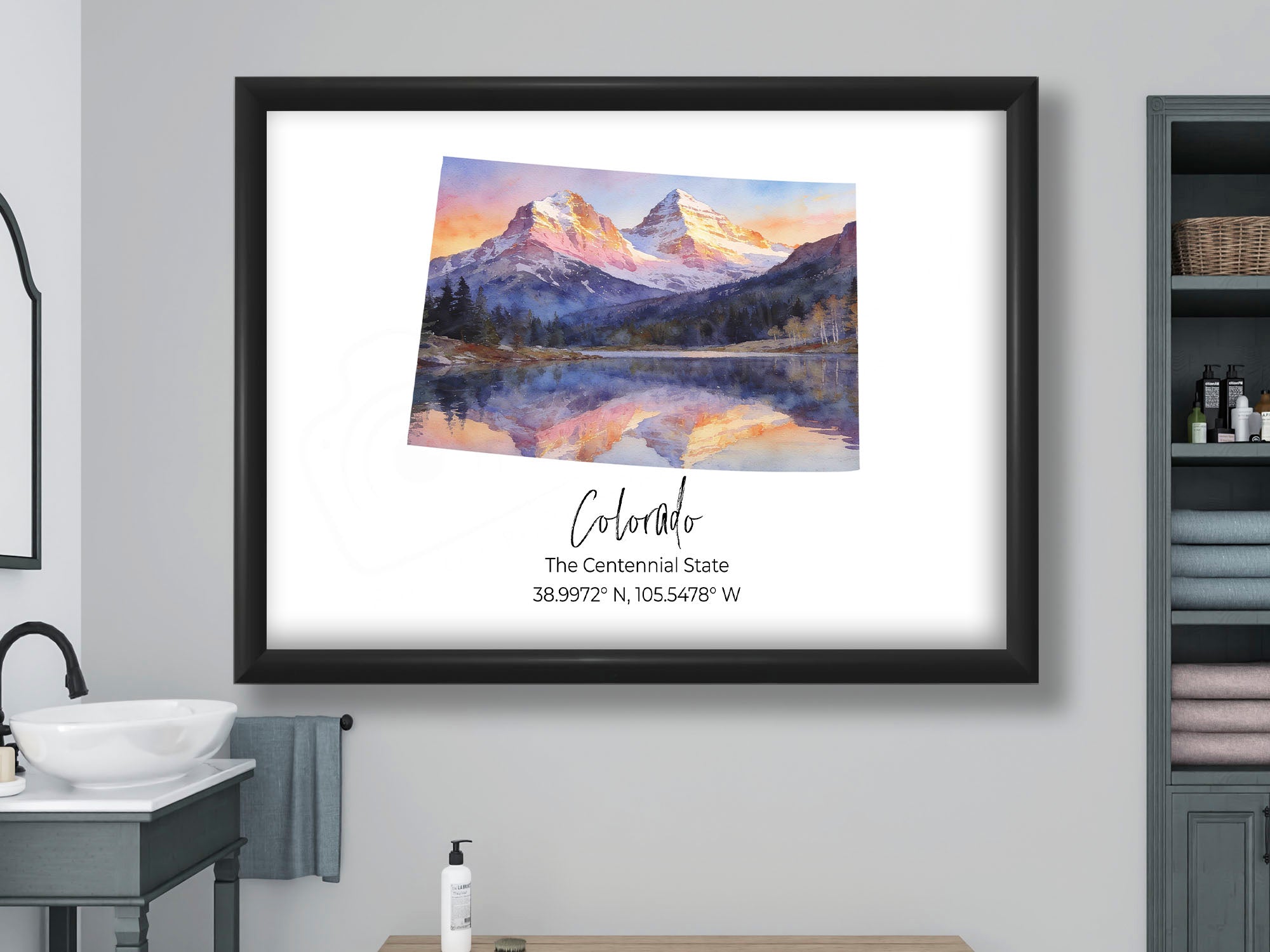 Colorado watercolor state map with Maroon Bells wall art print in black frame styled above a wooden bench in a bright bathroom