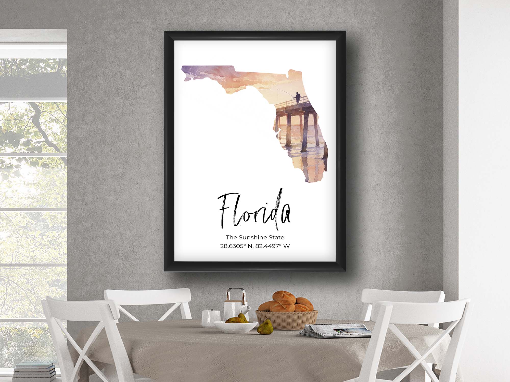 Florida watercolor state map with Venise Pier wall art print in black frame styled above a table and chairs in a bright dining room