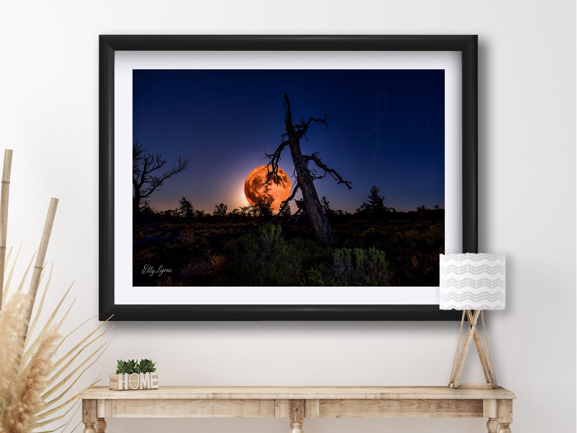 Strawberry full moon fine art print in black frame styled above a table in a bright entryway