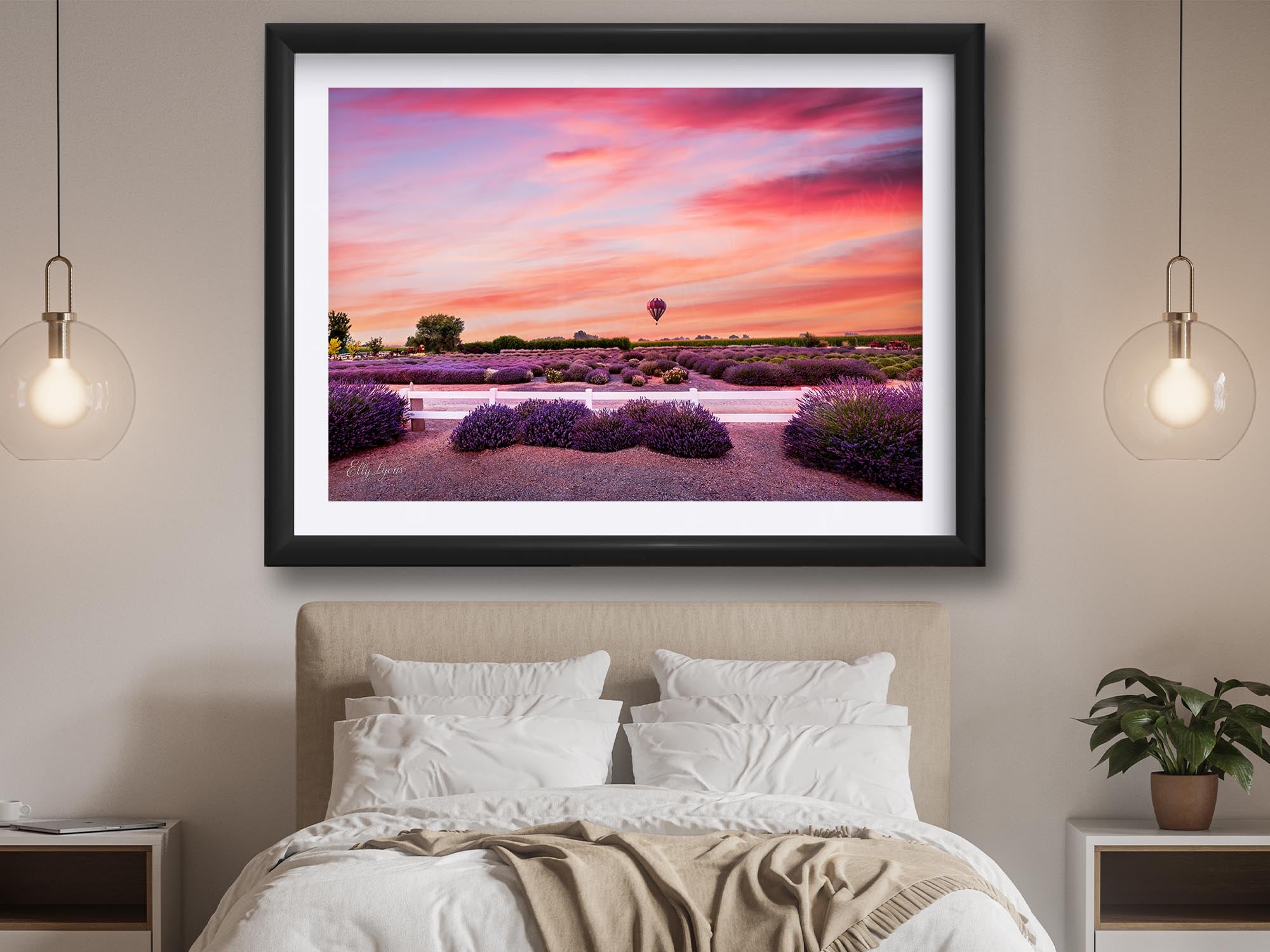 A hot air balloon over a lavender field during sunset fine art print in black frame styled above a bed in a bright bedroom