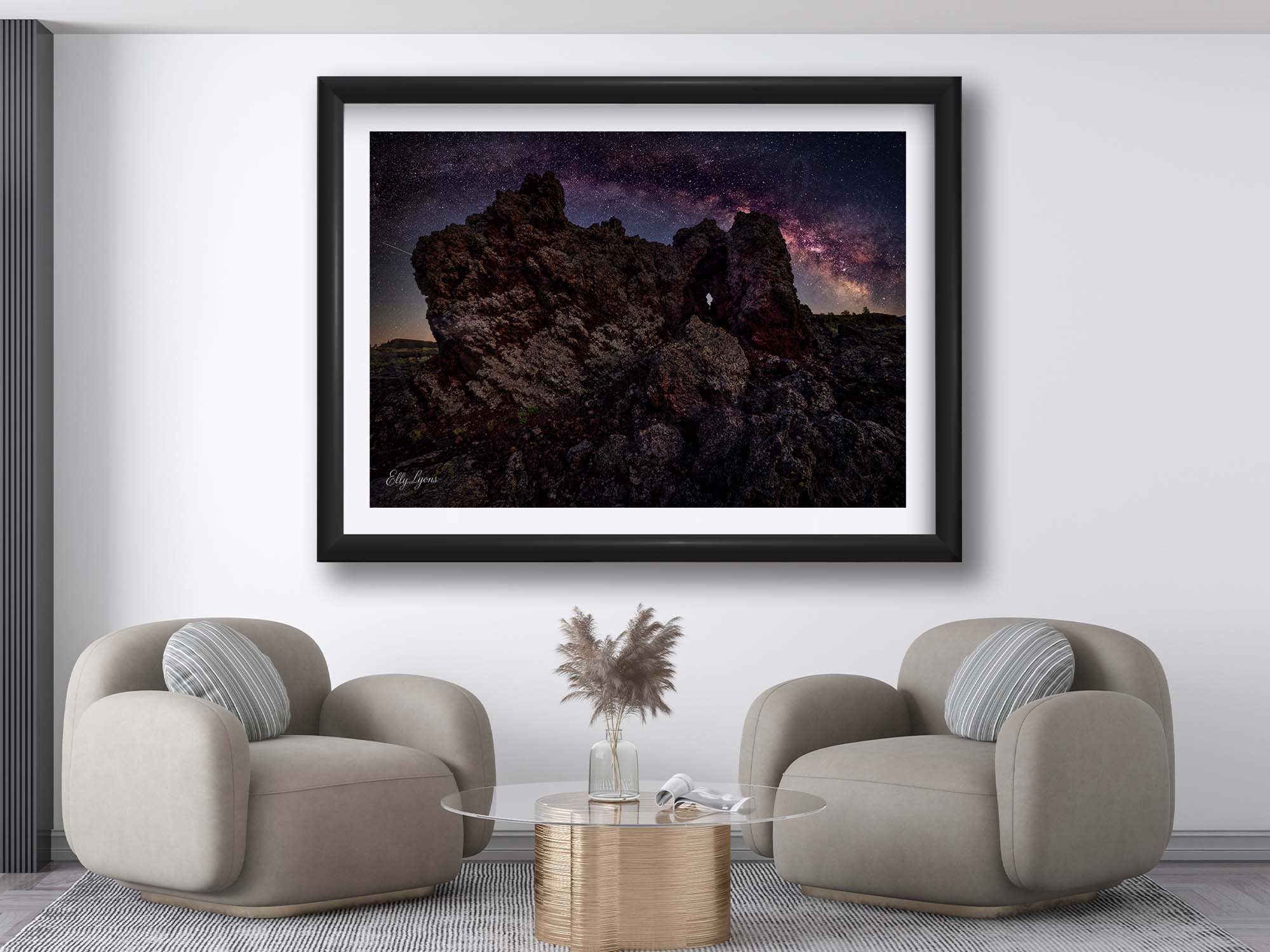 Craters of the Moon National Monument milky way stars fine art print in black frame styled above a two sitting chairs in a bright living room