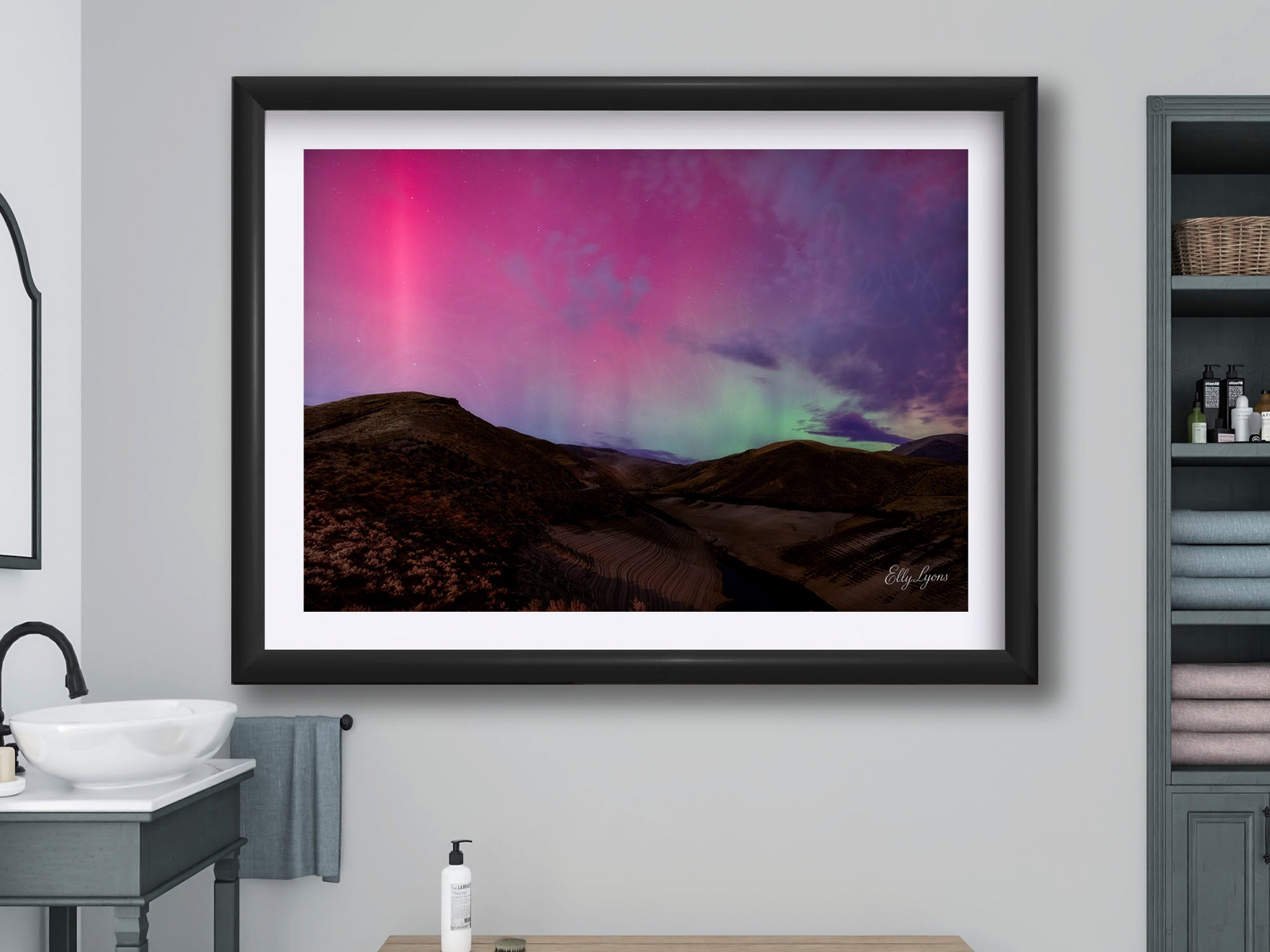 Northern lights over rolling desert hills at Lucky Peak in Idaho fine art print in black frame styled above a bench in a bright bathroom